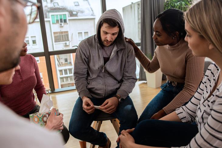 Diverse group of people sitting in circle in group therapy session