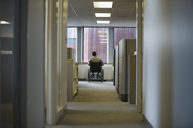 Man in a wheelchair looking out an office window